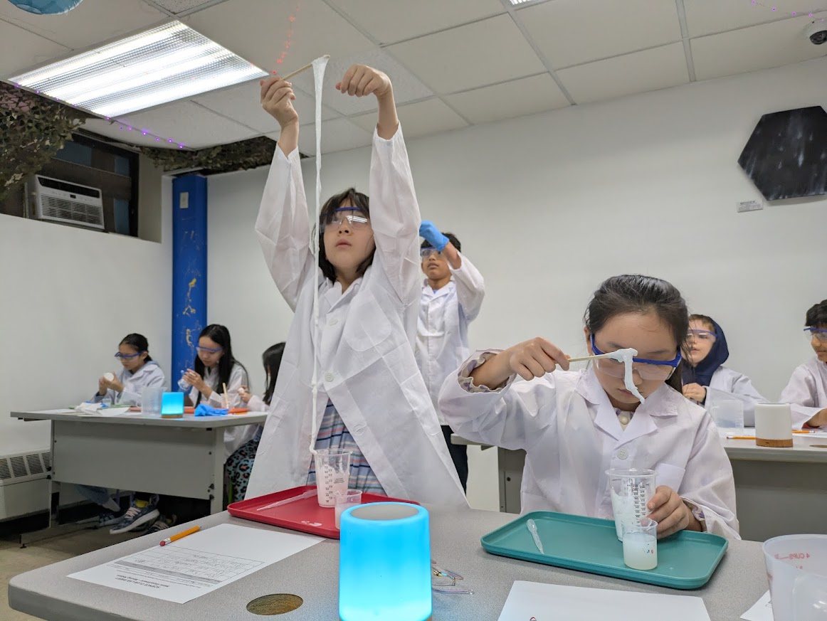 Students stretching long strands of polymer across the classroom