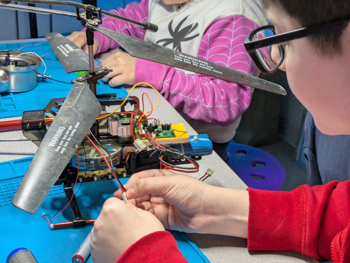 Students working inside an electric helicopter model