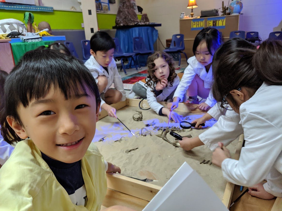Student smiling in front of a group paleontology excavation table