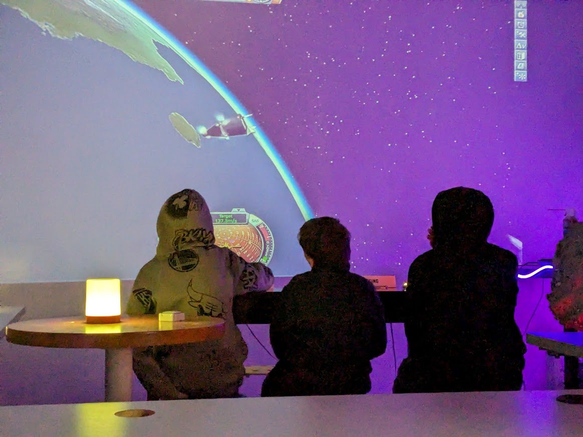 Students using a spaceflight simulation projected at room scale